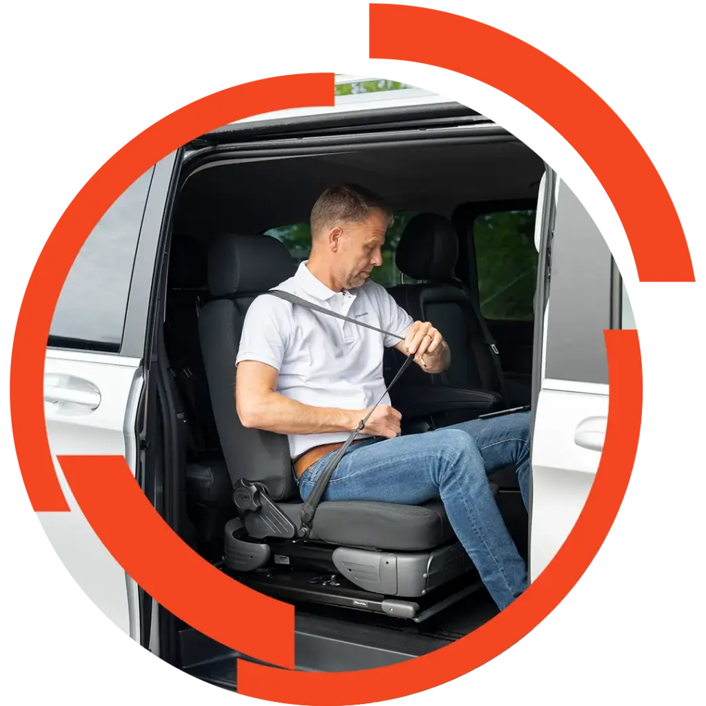 Mann in Freizeitkleidung sitzt in einem Vansitz und legt sich den Sicherheitsgurt an, geöffnete Schiebetür sichtbar.