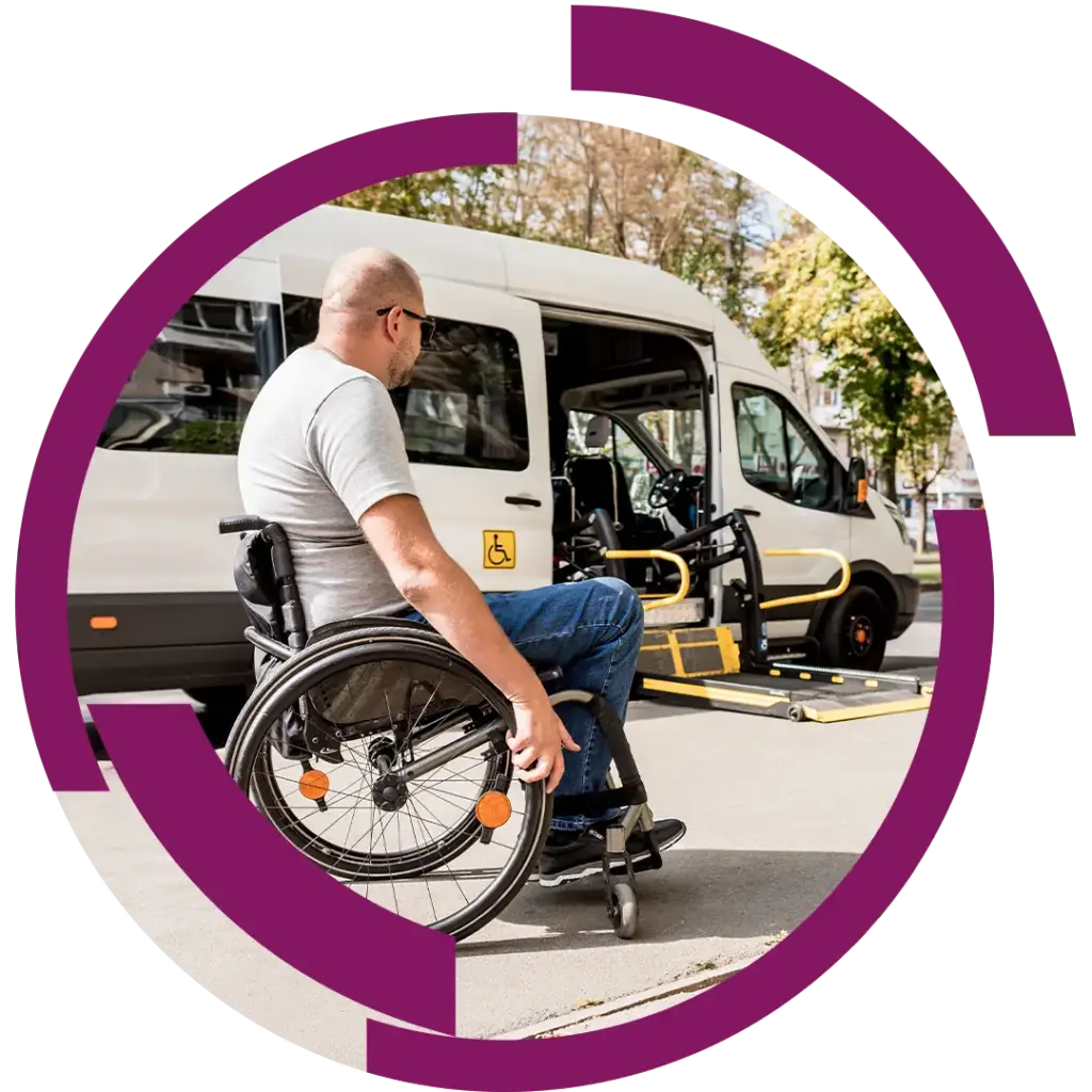 Mann im Rollstuhl nähert sich einem behindertengerechten Kleinbus mit ausgeklapptem Rampeinsatz für Ein-/Ausstieg