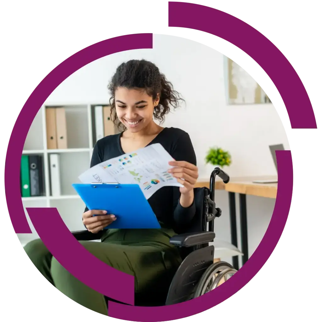 Junge Frau im Rollstuhl lächelt beim Lesen von Diagrammen auf einem Blatt, hält ein blaues Klemmbrett im Büro.