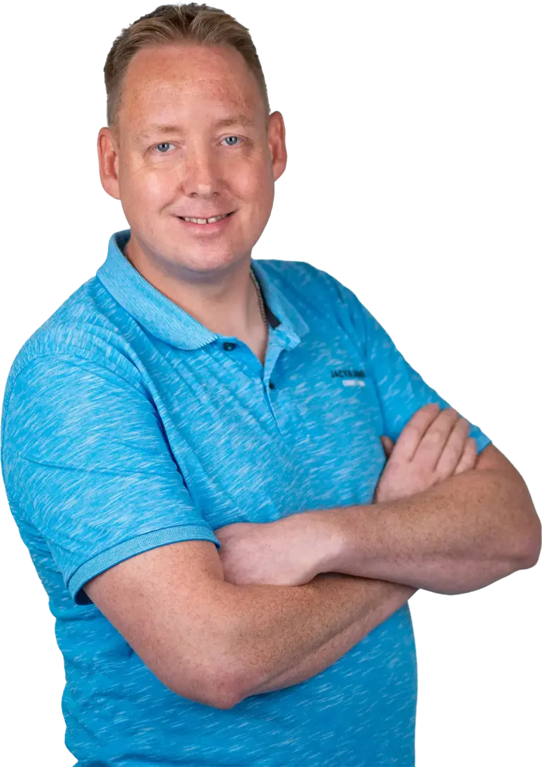 Mann mit blauer Polohemd im Halbporträt, lächelnd und die Arme vor der Brust verschränkt.